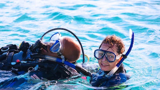 A man and woman in the water with scuba gear.