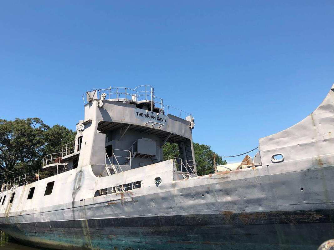 Old, abandoned ship under clear blue sky.