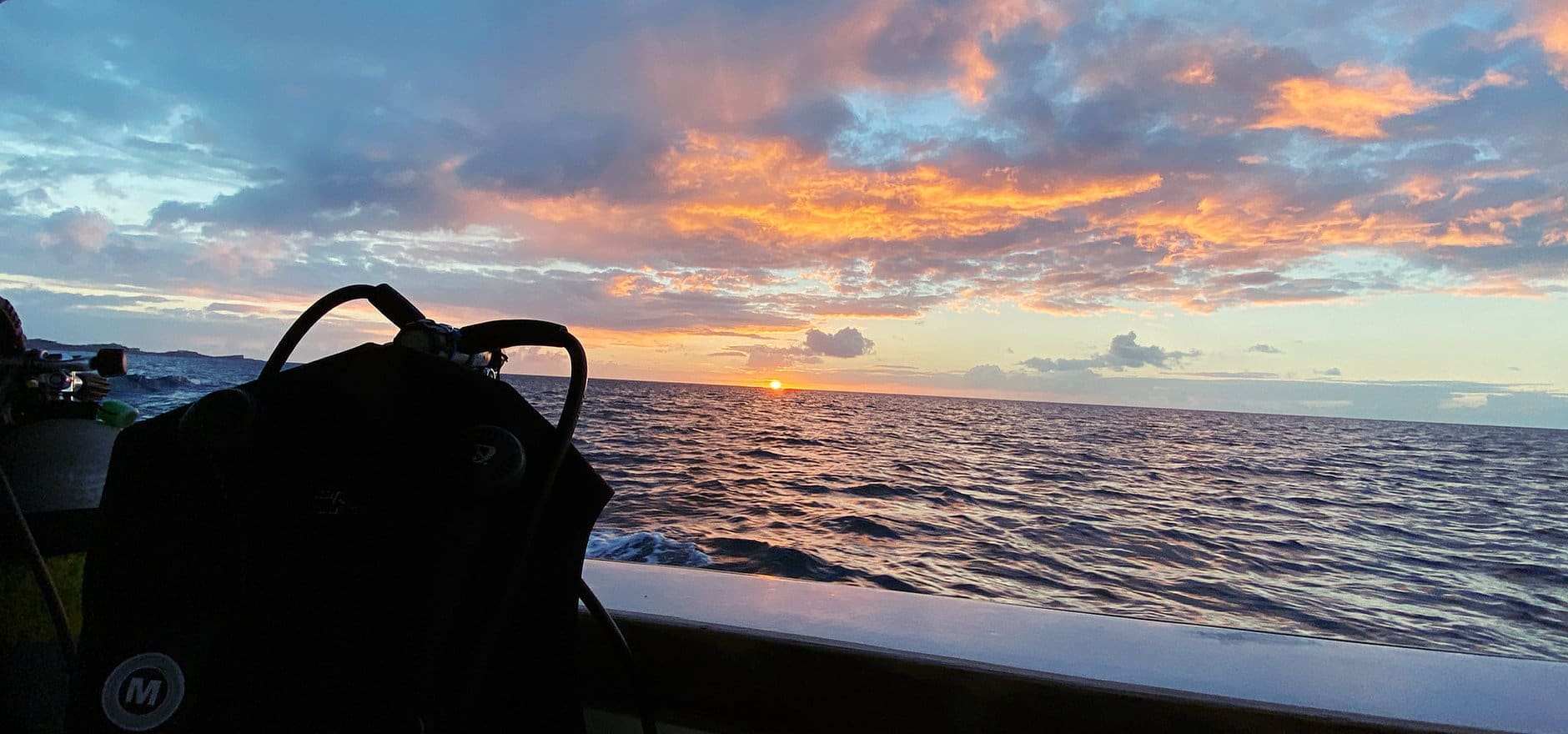 Ocean sunset with scuba gear on boat.