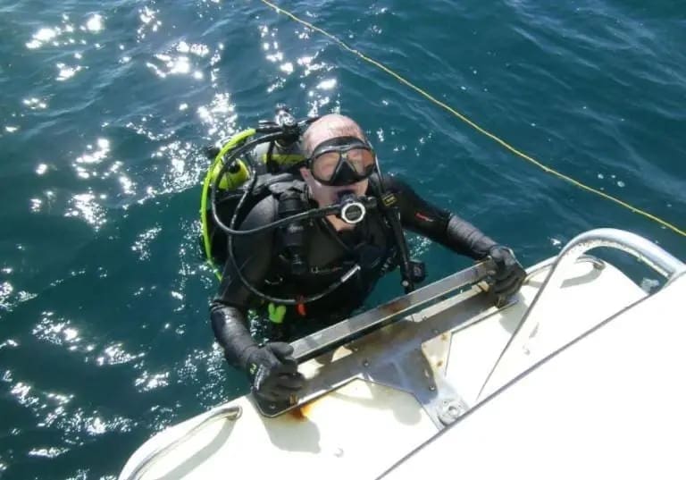 Scuba diver climbing onto a boat.