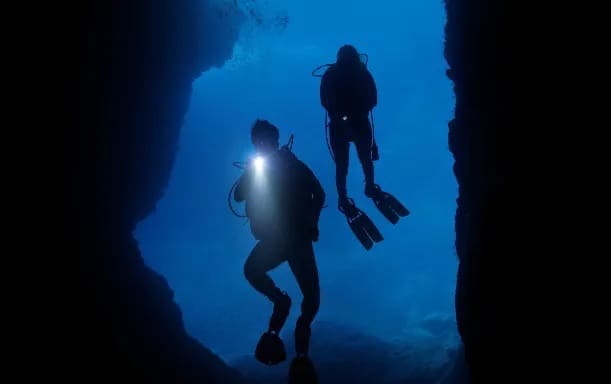 Two divers exploring underwater cave.
