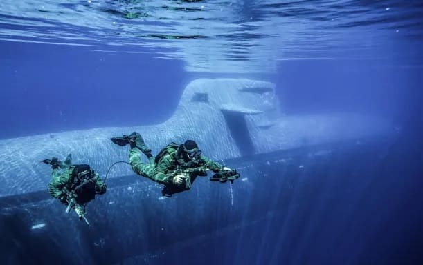 Divers swimming near submerged submarine.
