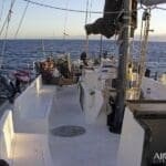 Sailboat deck with people relaxing at sea.