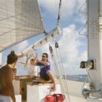People working on a sailboat at sea.