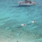 Boat and swimmers in clear turquoise water.