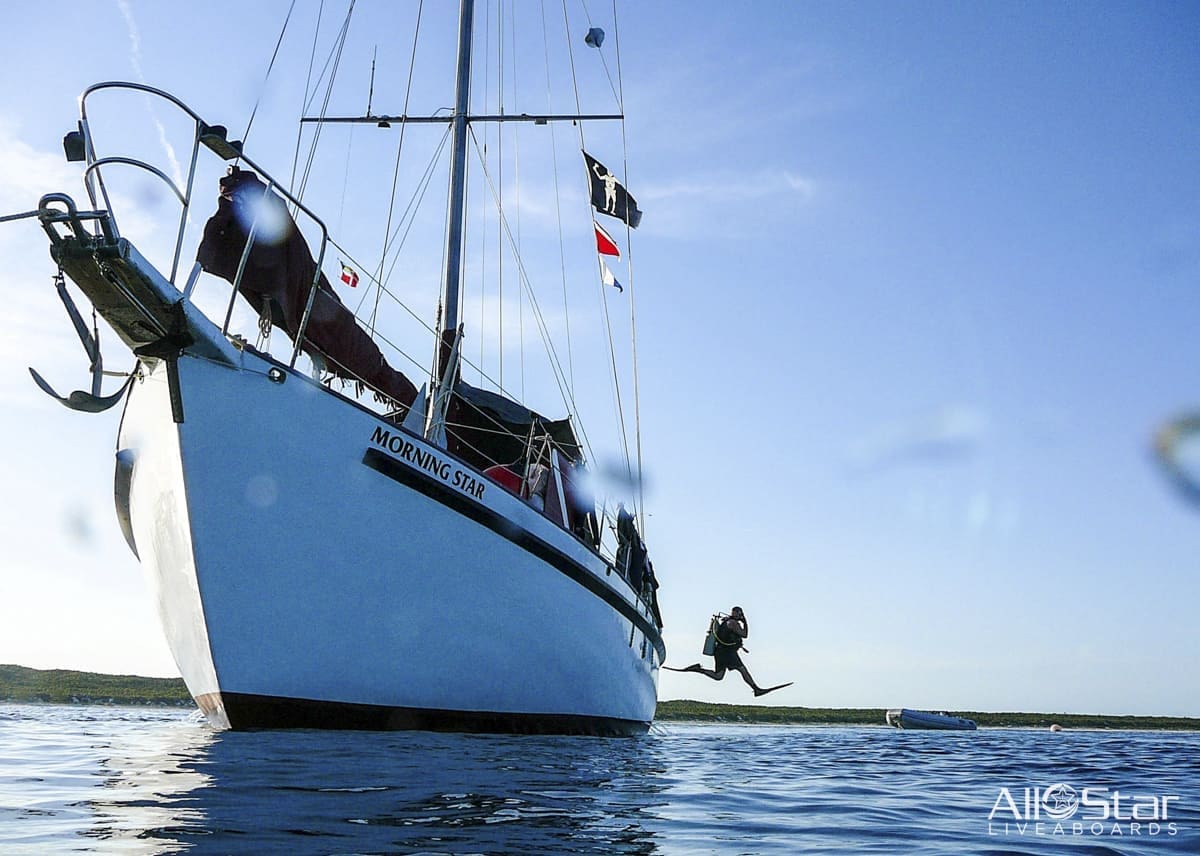 Sailboat with person jumping into water.