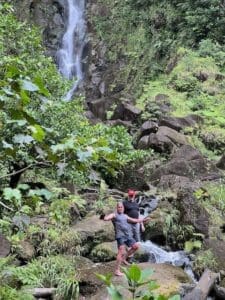 Two people hiking near a waterfall.