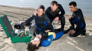 Divers performing first aid on the beach.