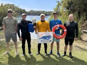 Group of divers holding rescue equipment outdoors.