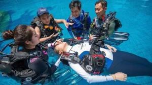 Scuba divers practicing rescue techniques in pool.