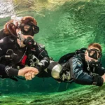 Two scuba divers underwater in clear water.