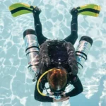 Scuba diver underwater with dual tanks.