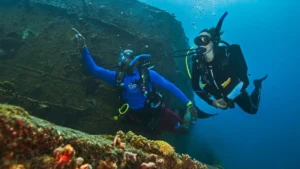 Scuba divers exploring underwater shipwreck together.
